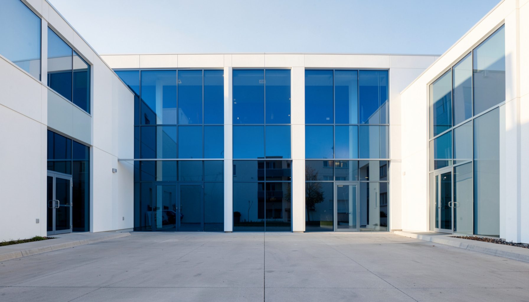 A clean, symmetrical architectural photograph of a modern public health facility with white walls and blue glass panels