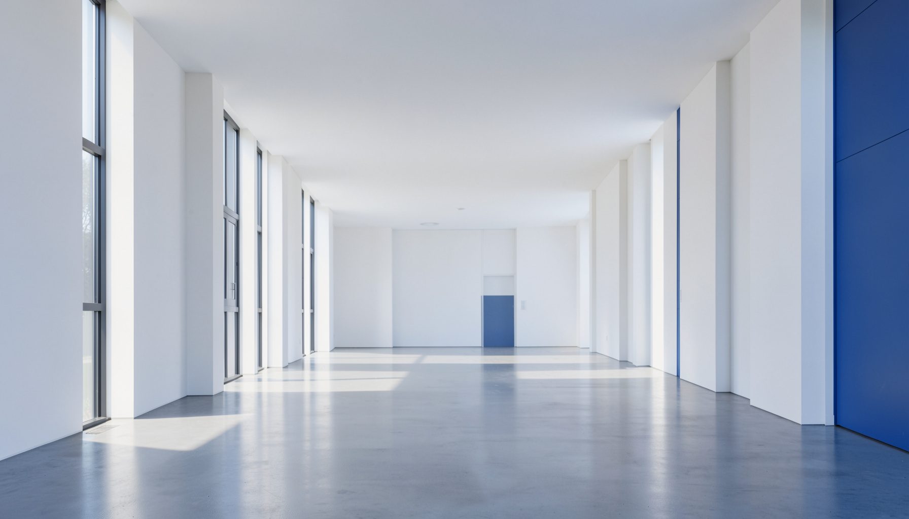 A wide, clean architectural photograph of a modern community health facility with strong symmetrical lines and white walls